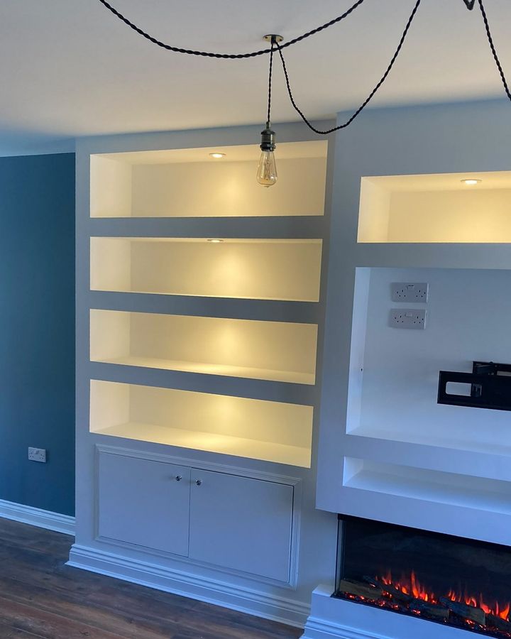 Media wall with lit shelving and an inset electric fire.