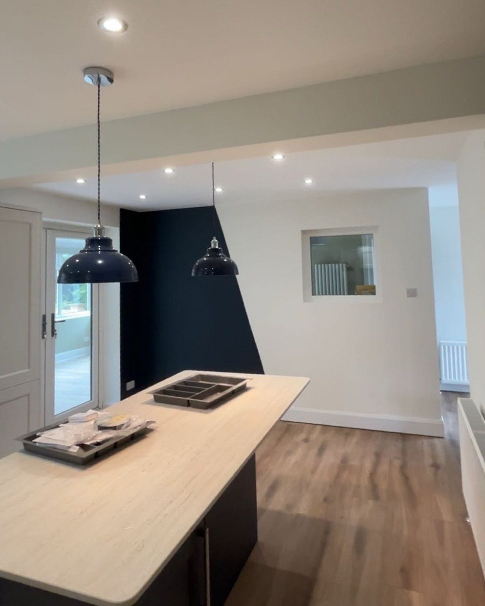 Open-plan kitchen in off-white with a navy feature wall