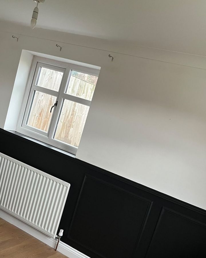 Black panelled walls below white in a dining room
